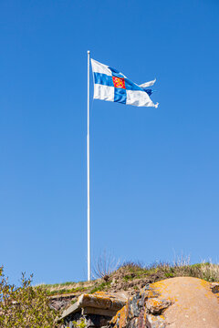 The Finnish flag set against a blue sky flying over the Suomenlinna Fortress at Kustaanmiekka on the island of Suomenlinna off Helsinki, Finland