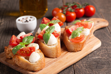 Tomato, basil and cheese fresh made caprese bruschetta. Italian tapas, antipasti with vegetables, herbs and oil on grilled ciabatta and baguette bread. Sandwich.