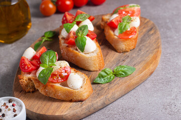 Fototapeta na wymiar Tomato, basil and cheese fresh made caprese bruschetta. Italian tapas, antipasti with vegetables, herbs and oil on grilled ciabatta and baguette bread. Sandwich.