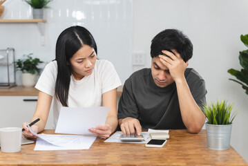 Fototapeta premium Stressed Asian couple looking at financial debt notice papers from bank.