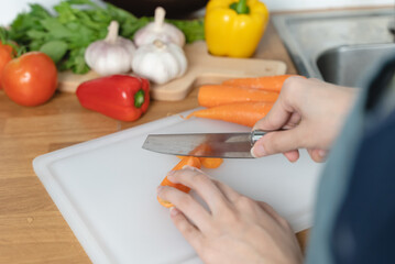 Asian housewife woman slice carrot to preparing salad ingredients for dinner meal  in the kitchen