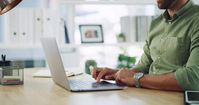 Closeup of modern businessman hands typing and working on his laptop in his casual office. Startup employee sitting at his desktop and answering emails to clients online, from remote workspace