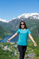 Naklejka na ściany i meble Happy woman in sunglasses with Geirangerfjord in the background