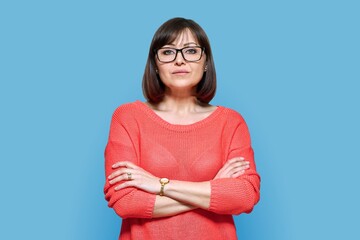 Serious confident middle aged woman on blue background