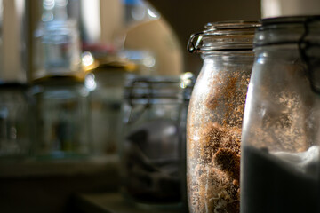 Glass jars full of provisions in a country pantry. Jars and tubs of all shapes and sizes in a...