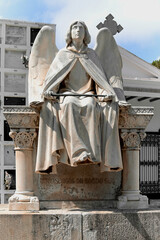 Angel looking to the sky over the grave of a dead person as a sign of remembrance and respect for the dead in the cemetery of Sitges. Concept of the Day of the Dead, All Saints Day and Halloween