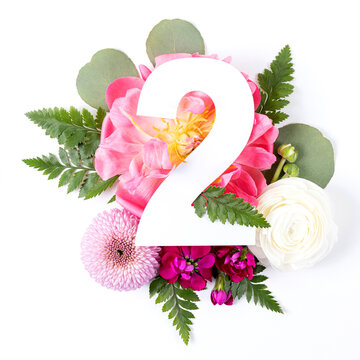 Creative layout with colorful flowers, leaves and number two isolated on white background. Anniversary concept. Flat lay.