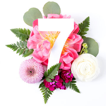 Creative layout with colorful flowers, leaves and number seven isolated on white background. Anniversary concept. Flat lay.