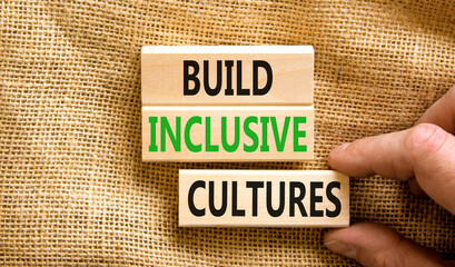 Build inclusive cultures symbol. Concept words Build inclusive cultures on wooden blocks. Businessman hand. Beautiful canvas background. Business build inclusive cultures concept. Copy space.