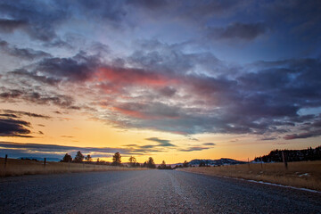 Fototapeta na wymiar Sunset or sunrise on an isolated and quiet country road outside of a small town in Montana Western USA