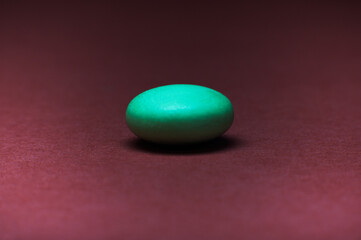 Obraz na płótnie Canvas Gründe Tablette isoliert auf roten Hintergrund - Grüne Pille auf rotem Grund