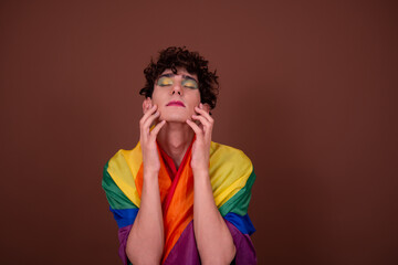 Young attractive guy in make-up posing in the studio. Pride Month.
