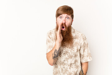 Young caucasian red-haired man isolated on white background is saying a secret hot braking news and...