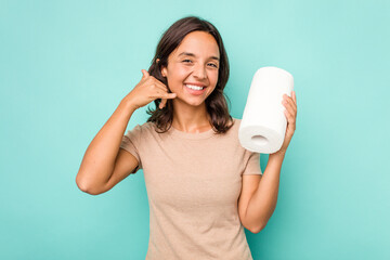 Young hispanic woman holding kitchen roll isolated on blue background showing a mobile phone call gesture with fingers.
