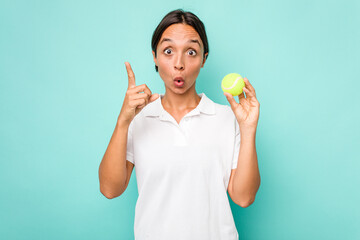 Young hispanic physiotherapy holding a tennis ball isolated on blue background having an idea, inspiration concept.