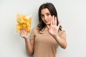 Young caucasian woman holding crisps isolated on yellow background standing with outstretched hand...