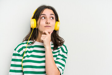 Young caucasian woman listening to music isolated on white background looking sideways with doubtful and skeptical expression.