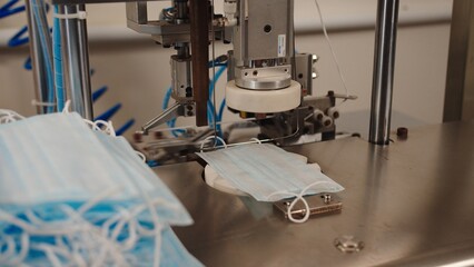 Medical mask on working table of machine. The process of soldering retainer to fabric mask