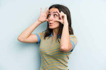 Young caucasian woman isolated on blue background keeping eyes opened to find a success opportunity.