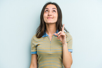 Young caucasian woman isolated on blue background indicates with both fore fingers up showing a...