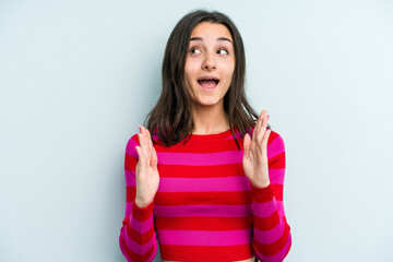 Young caucasian woman isolated on blue background receiving a pleasant surprise, excited and...