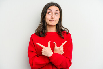 Young caucasian woman isolated on white background points sideways, is trying to choose between two options.