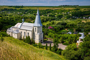 Catholic church in the Ukrainian village of Zinkiv. Rural landscape with a beautiful church on a summer day.