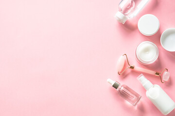 Skin care product, cream, soap serum, jade roller. Natural cosmetics on pink. Flat lay image with copy space.