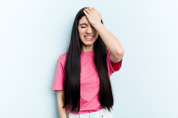 Young caucasian woman isolated on blue background forgetting something, slapping forehead with palm and closing eyes.