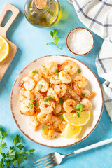 Fried shrimps with herbs and olive oil at blue table. Top view with space for your text.