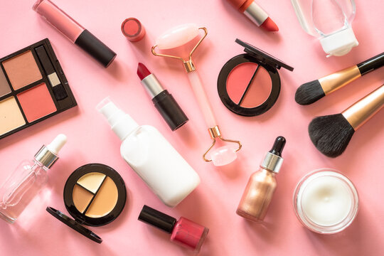 Makeup cosmetic products on pink background. Cream, lipstick, shadow and brushes. Flat lay image with copy space.