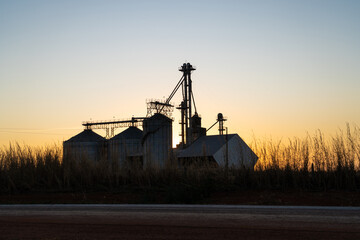 Beautiful silhouette view of silos in soybean farm and corn plantation at sunset on BR-163 road. Mato Grosso, Brazil. Concept of agriculture, ecology, environment, logistics, industry. © Imago Photo