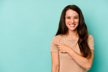 Young caucasian woman isolated on blue background smiling and pointing aside, showing something at blank space.