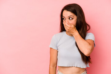 Young caucasian woman isolated on pink background thoughtful looking to a copy space covering mouth...