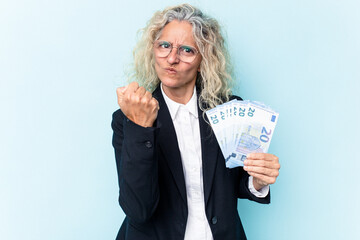 Middle age business caucasian woman holding bank notes isolated on white background showing fist to...