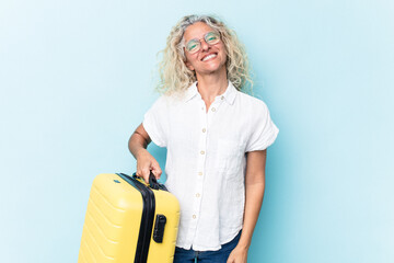 Young traveler man holding a suitcase isolated on white background happy, smiling and cheerful.