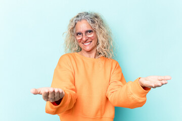 Middle age caucasian woman isolated on blue background showing a welcome expression.