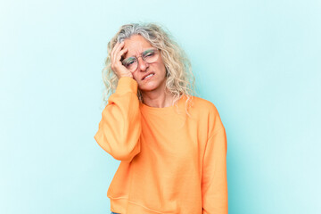 Middle age caucasian woman isolated on blue background tired and very sleepy keeping hand on head.