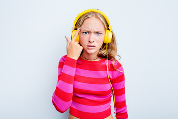 Caucasian teen girl listening to music isolated on blue background showing a disappointment gesture with forefinger.