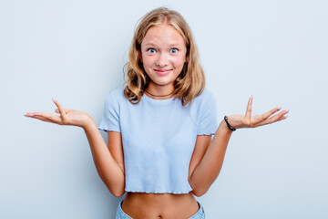 Caucasian teen girl isolated on blue background doubting and shrugging shoulders in questioning...