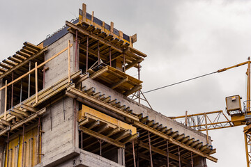 Building construction site next to a crane against a cloudy sky