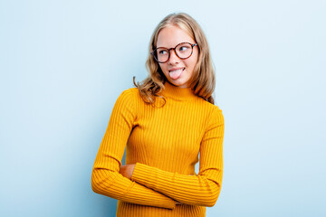 Caucasian teen girl isolated on blue background funny and friendly sticking out tongue.
