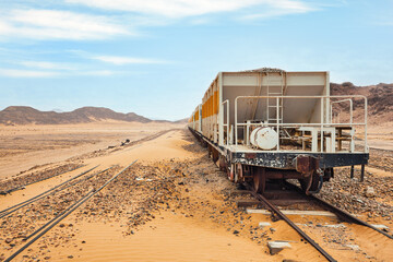 Old unused train at Wadi Rum train station, sandy desert around