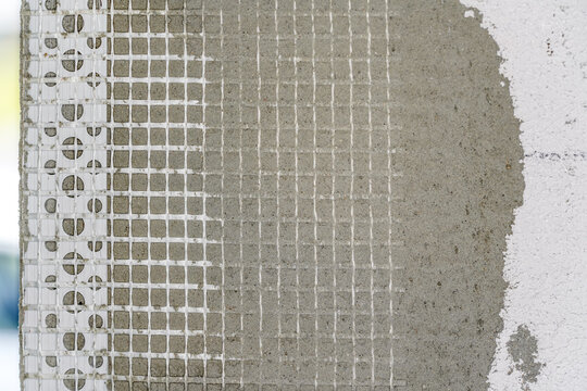 Bare wall in new house construction site with plastic reinforcement net under mortar, closeup detail