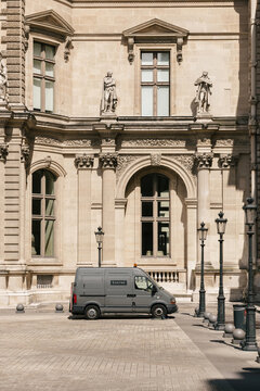 Paris, France - Aug 18, 2014: Gray van with Louvre inscription parked somewhere on a Paris street near beautiful architecture building