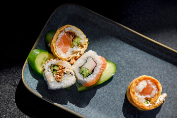 Appetizing sushi close-up. Maki and rolls with tuna, salmon, shrimp, crab and avocado. Top view of a variety of sushi on a dish.