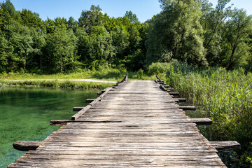 Old, wooden bridge passing over beautiful Korana river flowing directly from Plitvice national park lakes, Croatia