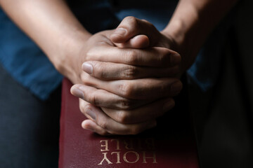 Hands together in prayer to God along with the bible In the Christian concept of faith,...