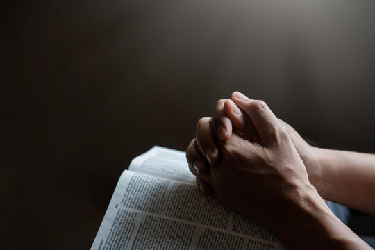 Hands together in prayer to God along with the bible In the Christian concept of faith, spirituality and religion, men pray in the Bible. prayer bible