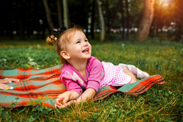 Cute little girl laughing on the grass looking up.